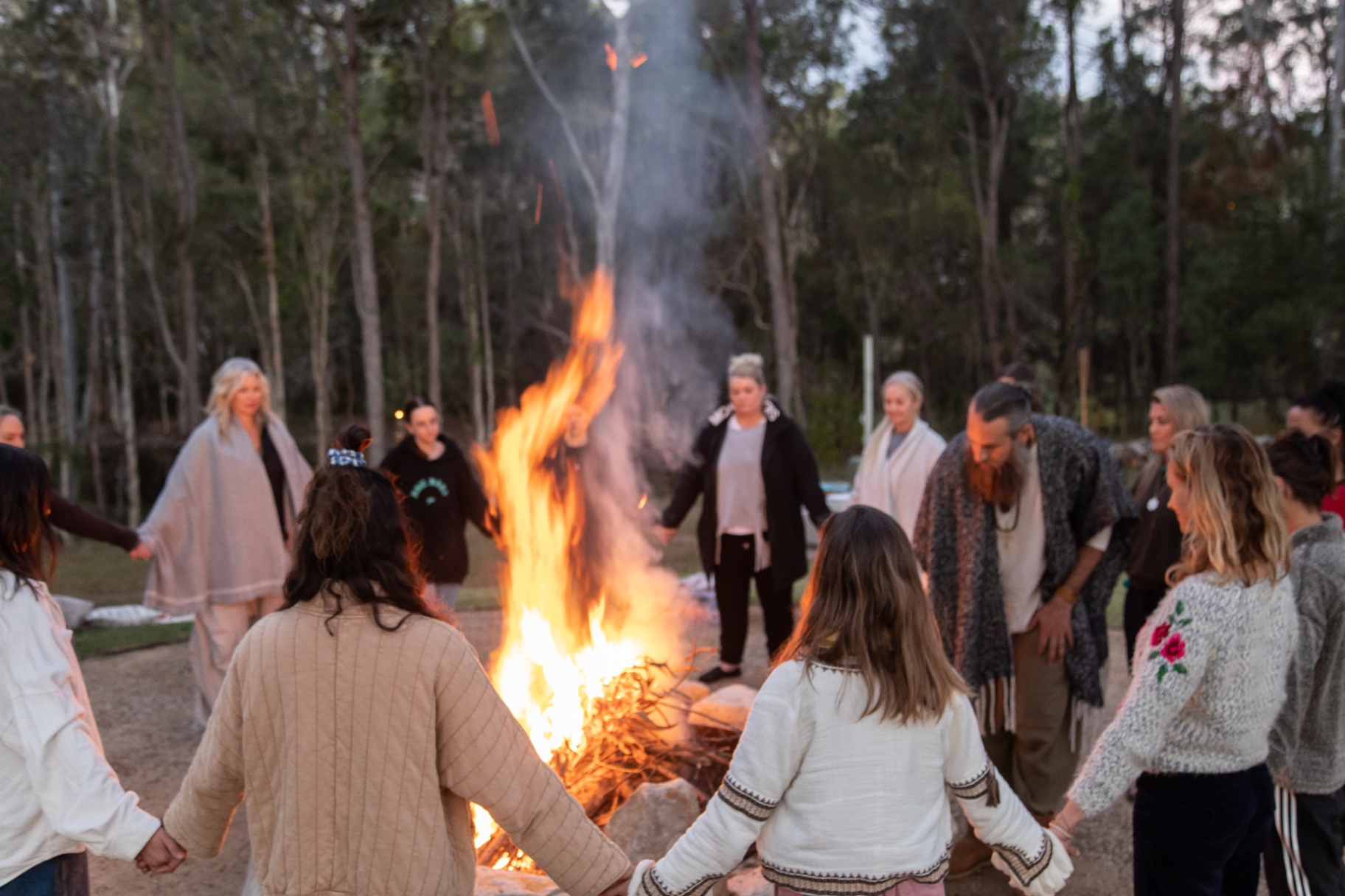 Circle holding hands around a tall fire